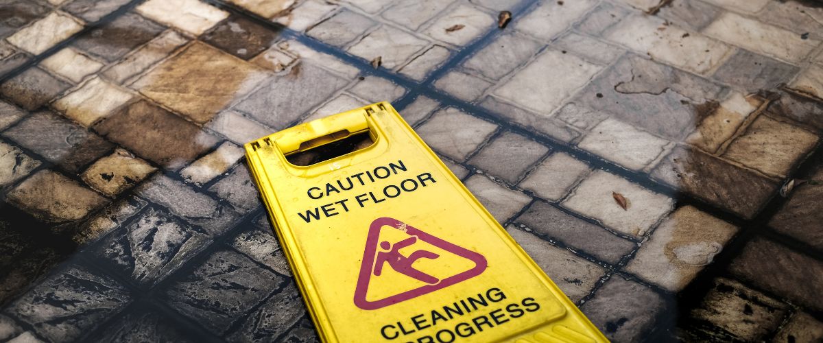a yellow wet floor sign that has fallen down, creating a possible slip and fall situation
