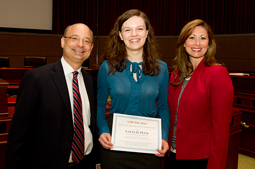 Award-winning student recognized by smiling man and woman, likely educators or administrators.