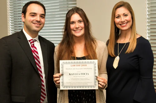 Smiling law student awarded certificate by injury attorneys, highlighting firm's commitment to mentorship.