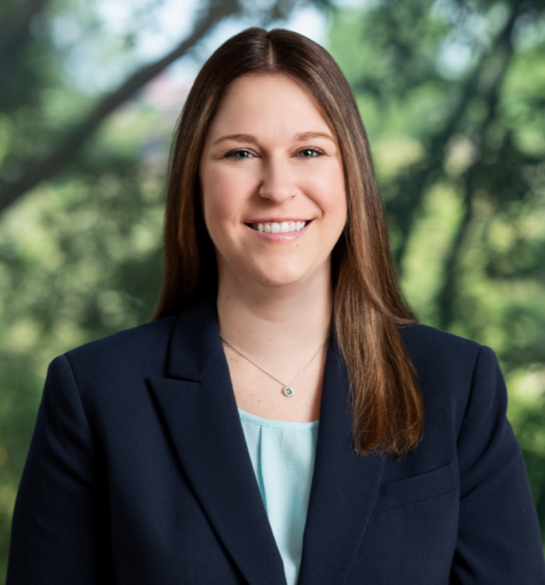 Young smiling professional woman in suit jacket outdoors, warm welcoming expression, legal services