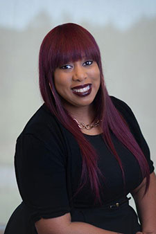 Smiling Asian woman with long burgundy hair wearing black shirt, injury attorney website headshot