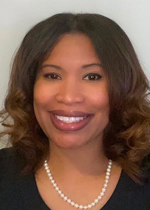 Smiling African American woman wearing pearl necklace and black top, professional headshot