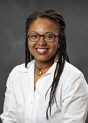 Smiling African American woman wearing glasses and a white collared shirt, an approachable professional portrait.