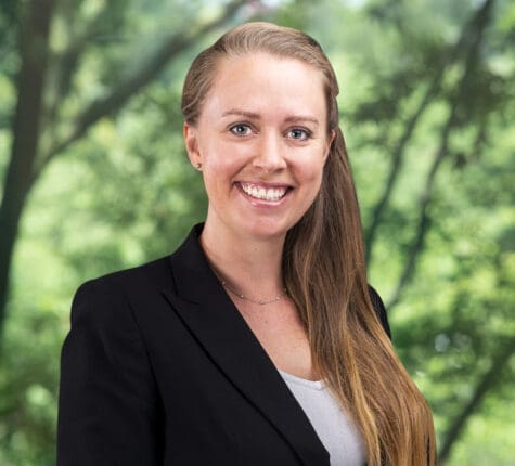 Smiling female attorney portrait in park setting, professional headshot for legal website