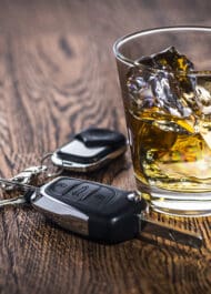 Glass of whiskey and car keys on wood table - Dangers of drinking and driving | Injury Attorney