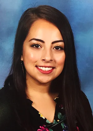 Young smiling woman with long dark hair on blue background, professional headshot for attorney website
