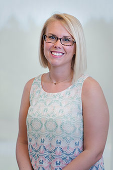 Smiling blonde woman wearing glasses and colorful blouse, potential client for injury attorney services.