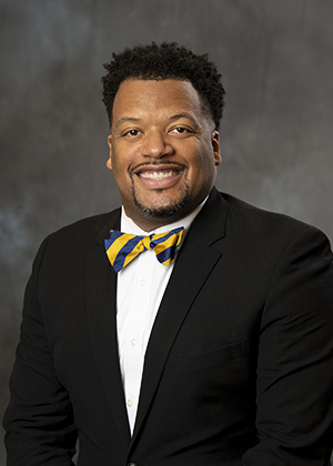 Smiling African American man in suit and bowtie, professional headshot for injury attorney website.