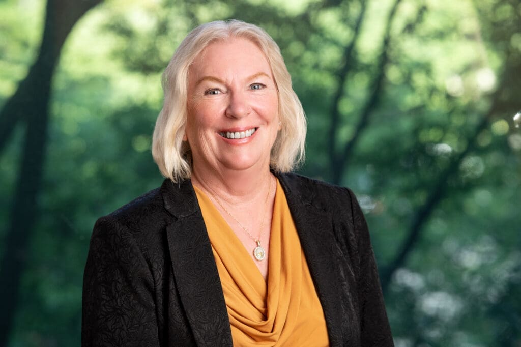Smiling mature lawyer portrait against lush green trees, experienced injury attorney ready to help