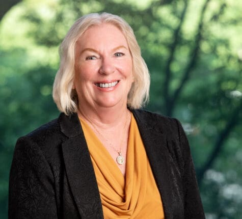 Smiling mature lawyer portrait against lush green trees, experienced injury attorney ready to help