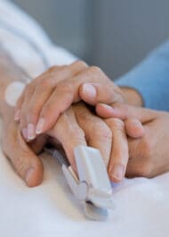 Closeup of doctor holding elderly patient's hand, providing compassionate medical care and support.