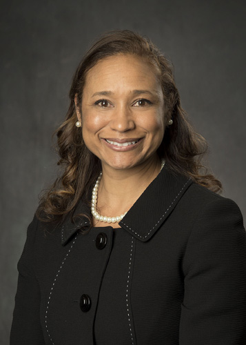 Smiling female attorney with pearl necklace, professional headshot for legal services website.
