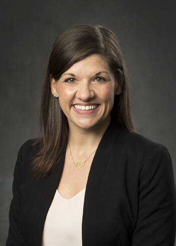 Smiling female attorney in black suit jacket, optimistic and approachable, ready to help with your legal needs.