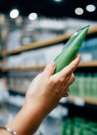 Alt text: Hand selecting green aloe vera leaf from store shelf for natural pain relief and skin treatment