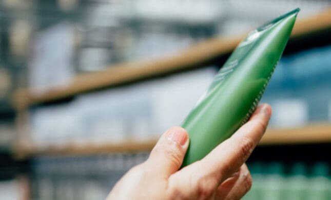 Alt text: Hand selecting green aloe vera leaf from store shelf for natural pain relief and skin treatment