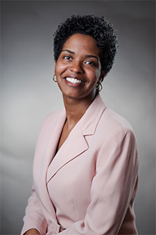 Smiling African American woman wearing pink blazer, professional headshot for injury attorney website.