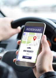 Rideshare app on smartphone in driver's hand, requesting new ride. Injured in rideshare accident?