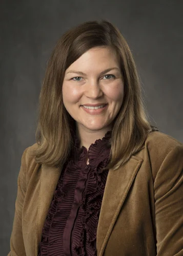 Smiling woman in brown suit jacket, ready to provide trusted legal counsel for your injury case.