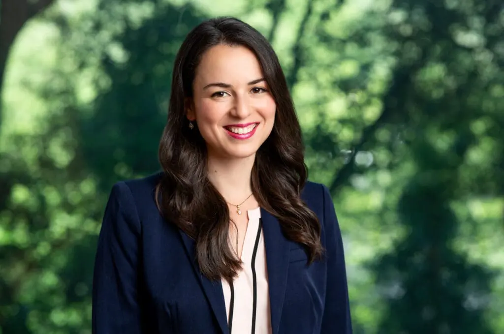 Professional headshot of smiling brunette woman wearing blue blazer, suitable for attorney profile page