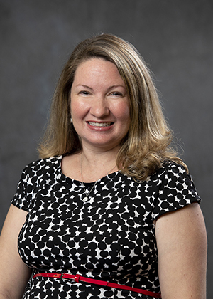 Smiling blonde woman in black and white patterned dress, professional headshot for attorney website.