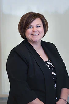Smiling female attorney in black blazer, ready to assist with injury cases - SEO alt text
