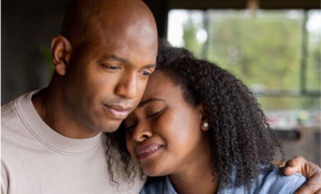 Compassionate African American couple embracing, providing emotional support during difficult times.