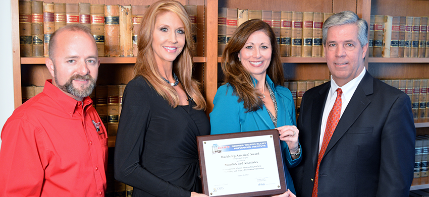 Injury attorneys present award to smiling woman in front of law library shelves. Concise, SEO-friendly alt text for a legal website.
