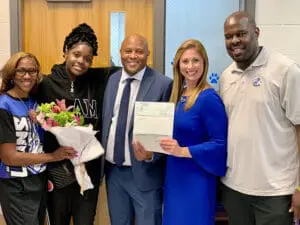 Family receiving settlement check from smiling attorney at law office, representing successful case resolution.