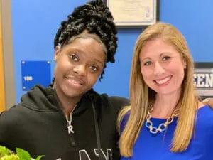 Young African American client smiling with blonde female attorney in professional office setting