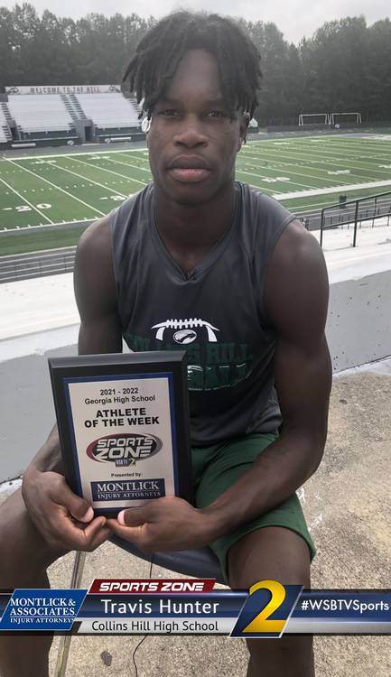 Athlete of the Week Travis Hunter holding Sports Zone award at Collins Hill High School football field
