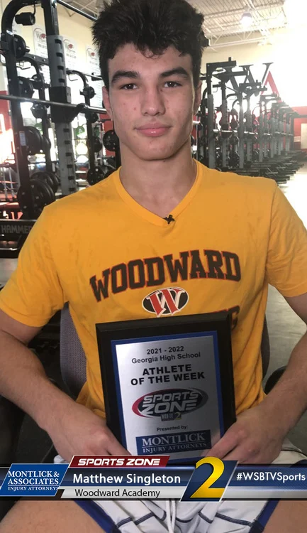 Young male Woodward Academy athlete of the week poses in weight room holding Sports Zone plaque