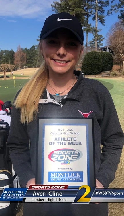 Young female high school athlete holding plaque for "Athlete of the Week" award on golf course