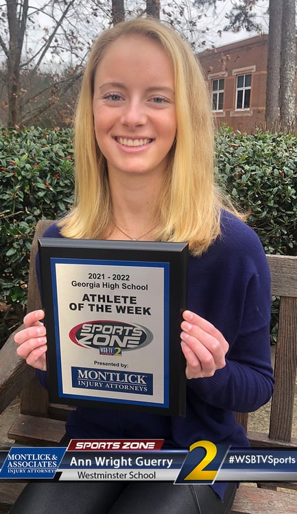 Smiling female Westminster School athlete of the week holds award plaque outside brick building