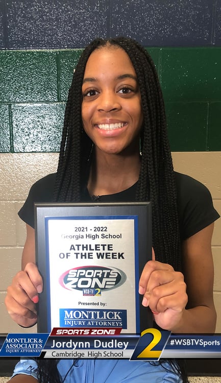 Smiling student athlete of the week holds award plaque from local high school sports program.