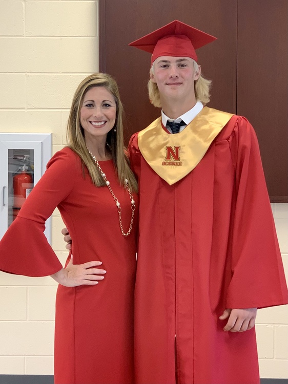 Young woman in red dress and smiling graduate in cap and gown pose together at university graduation