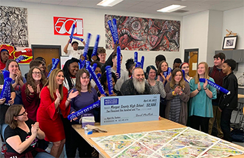Diverse group celebrates winning settlement check from successful personal injury case at law office.