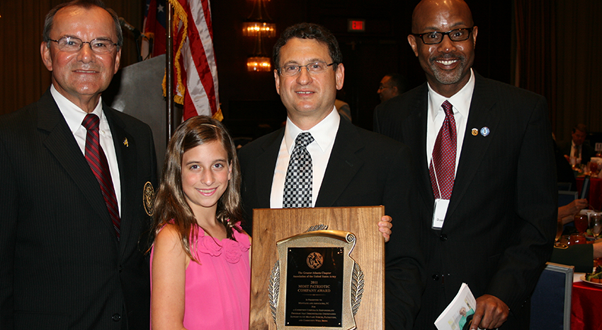 Family celebrates their daughter receiving academic achievement award from local officials.