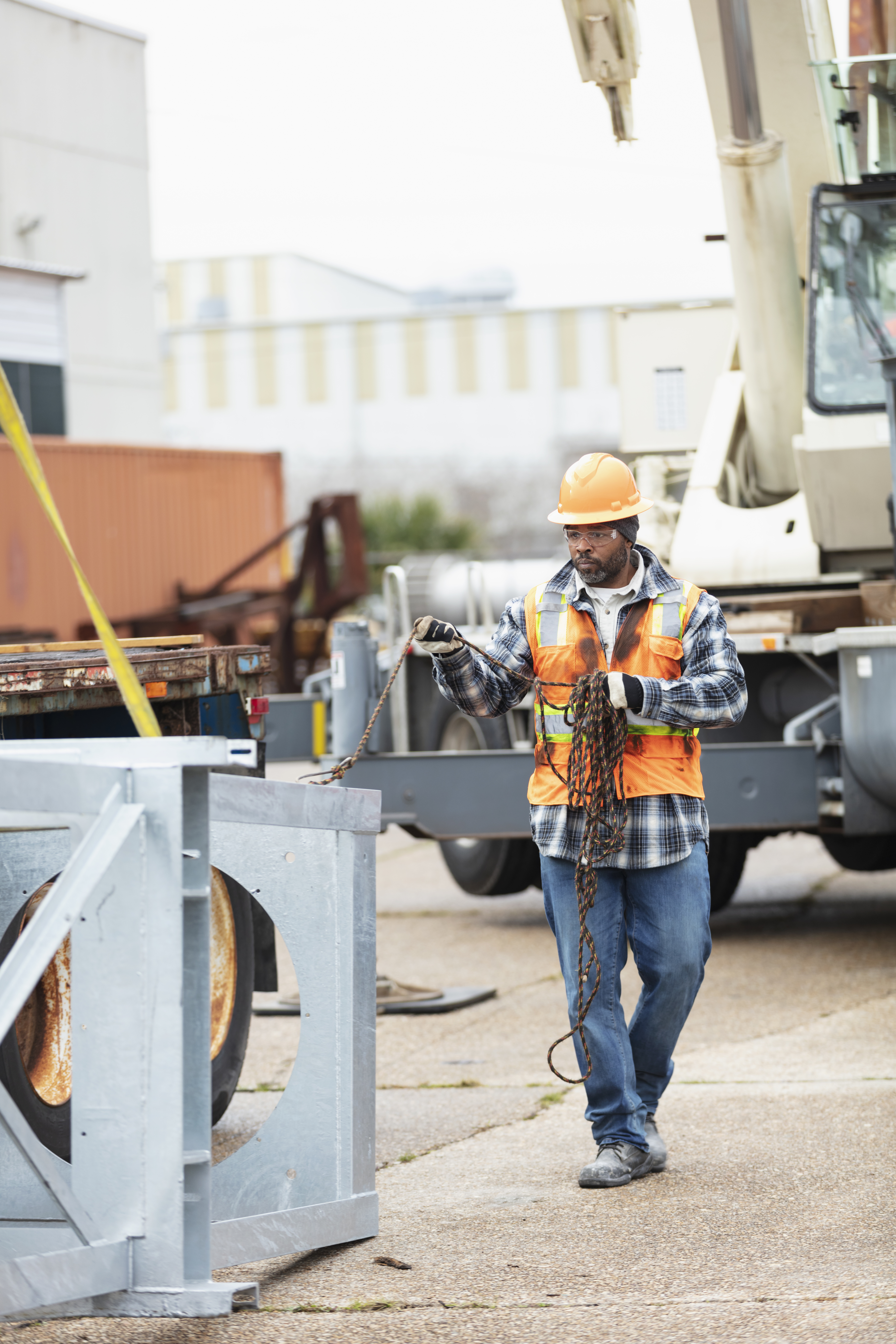 A man in a hard assisting crane operator lifting object