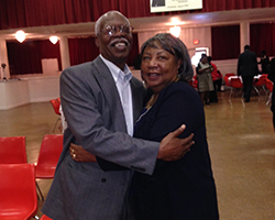 Smiling Black couple hugging in auditorium. Experienced attorneys caring about clients.