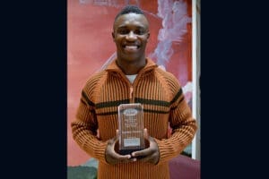Smiling man holding personal injury attorney award in front of colorful artistic background, SEO alt text.