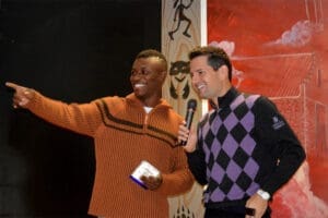 Smiling comedians on stage at comedy show, one pointing while other laughs. Entertainment accident law.