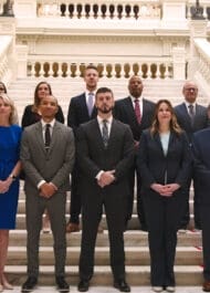 Group portrait of diverse legal team standing on ornate government building stairs, appearing professional and confident