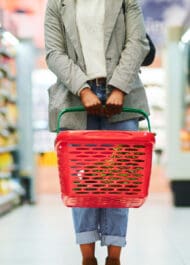 Woman carrying red shopping basket in grocery store aisle, representing slip and fall accident risk
