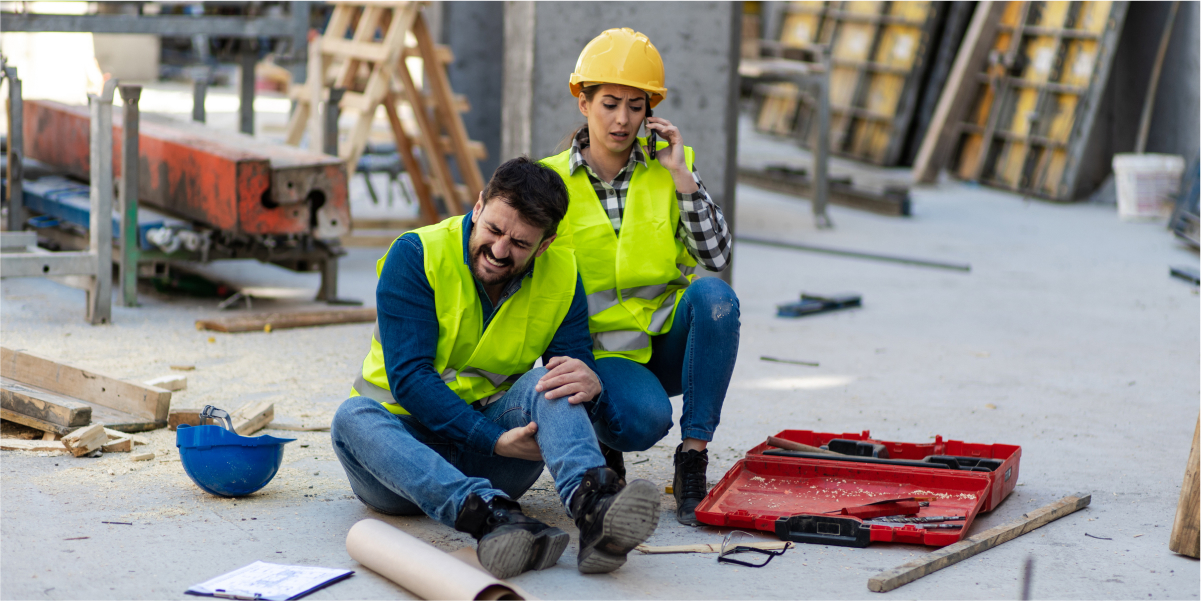Injured construction worker discussing accident with concerned colleague at job site. Call for legal help.