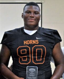 SEO alt text: African American high school football player in black jersey with number 90, smiling confidently