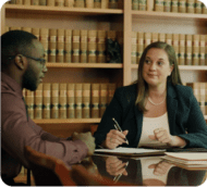 Two lawyers reviewing case documents in a law library, focused on resolving a client's legal matter.