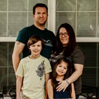 Smiling family portrait of father, mother, son and daughter at home. Caring injury attorney helps families.