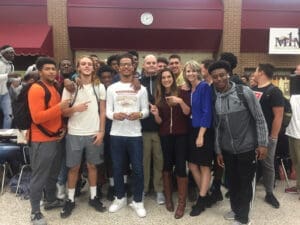 Group of diverse young students standing together outside school building, smiling at camera