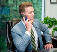 Lawyer in suit on phone at desk, thoughtful expression. Personalized attention for your legal needs.
