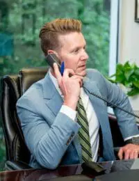 Lawyer in suit on phone at desk, thoughtful expression. Personalized attention for your legal needs.